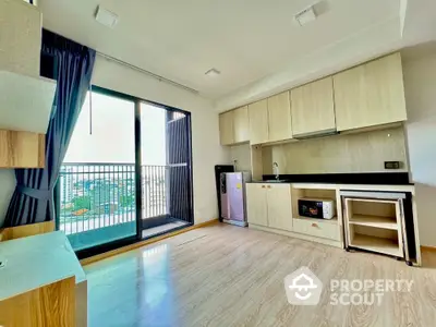 Modern kitchen with open layout and balcony view, featuring sleek cabinetry and hardwood floors.