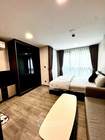 Modern bedroom with large window and stylish furnishings in a contemporary apartment.