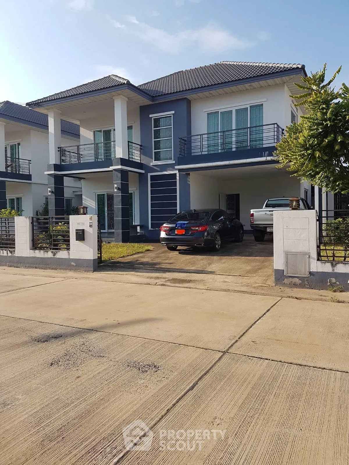 Modern two-story house with driveway and parked cars in a suburban neighborhood.