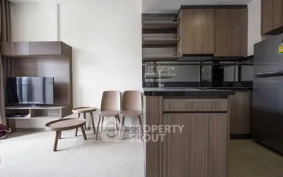 Modern open-layout kitchen and living area with sleek wooden cabinetry and stylish furniture.
