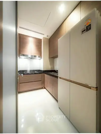 Modern kitchen with sleek cabinetry and large refrigerator in a compact layout.