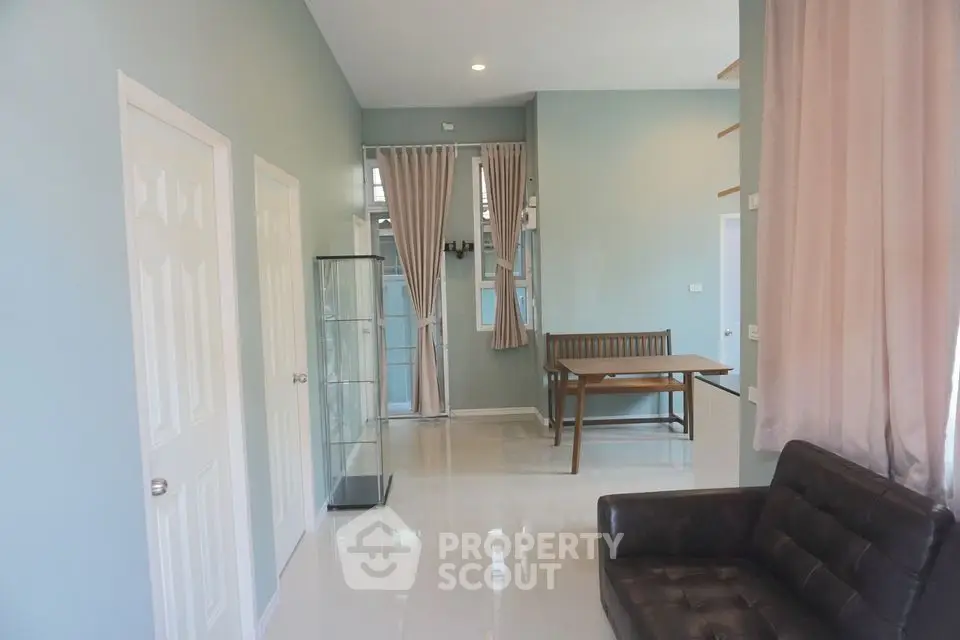 Spacious and bright living area with glossy tiled floors, modern furniture, and large windows draped with stylish curtains, perfect for comfortable urban living.