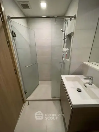 Modern bathroom with glass shower and sleek vanity in contemporary apartment.