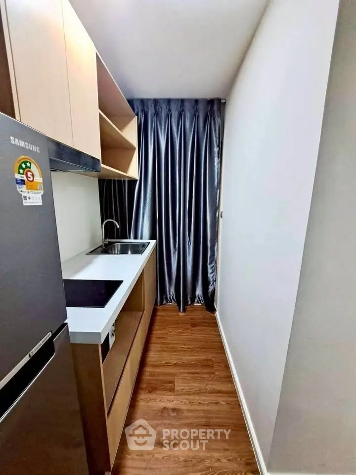 Modern compact kitchen with sleek cabinetry and stainless steel appliances in a cozy apartment.