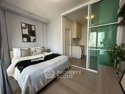 Modern bedroom with stylish decor and sliding glass door leading to compact kitchen area.