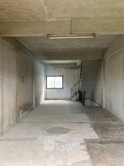 Spacious unfinished room with concrete walls and window, ideal for customization.