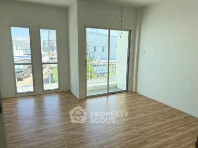 Bright empty room with large windows and sliding glass door to balcony.