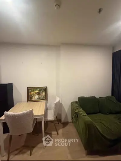 Cozy living room with green sofa and dining table, perfect for relaxation and dining.