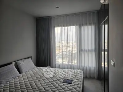 Modern bedroom with large window and city view, featuring a comfortable bed and stylish decor.