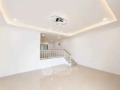 Spacious modern living room with elegant ceiling light and staircase, perfect for family gatherings.