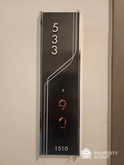 Modern apartment door number sign with sleek design and metallic finish