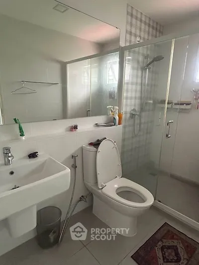 Modern bathroom with glass shower, sink, and toilet in sleek design.