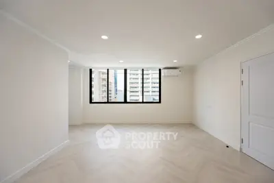 Spacious empty room with large windows and modern flooring in a high-rise building.