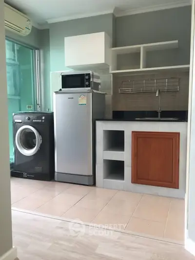 Modern kitchen with washing machine, fridge, and microwave in compact layout.