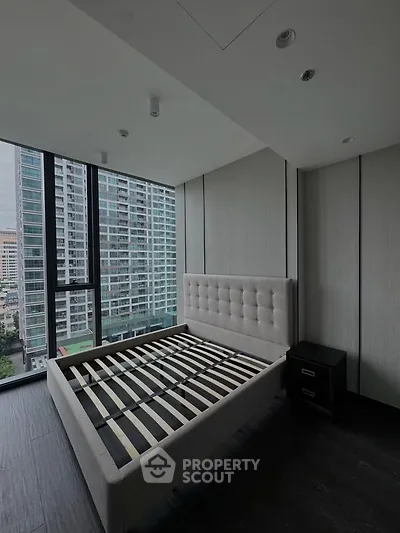 Modern bedroom with large windows and city view in a high-rise apartment.