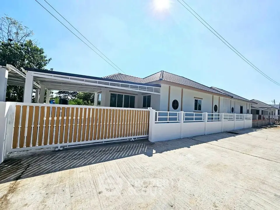 Modern single-story house with spacious driveway and fenced yard under clear blue sky.