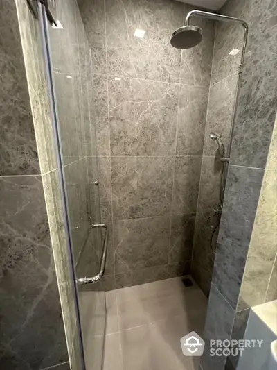 Modern bathroom with sleek marble tiles and a spacious shower area.