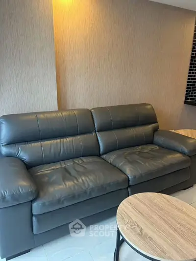 Modern living room with sleek black leather sofa and stylish wooden coffee table