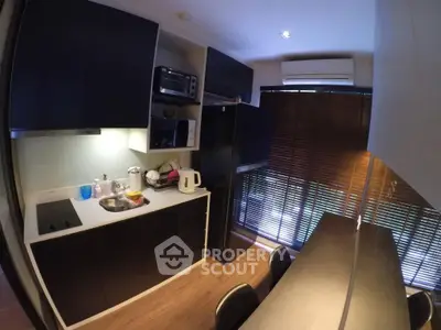 Modern kitchen with sleek black cabinets and dining area, featuring natural light and contemporary appliances.