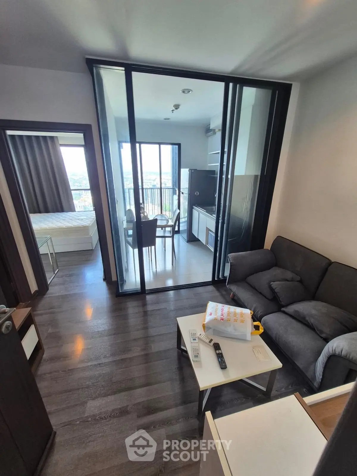 Modern apartment interior with glass-enclosed dining area and cozy living room, featuring sleek design and natural light.