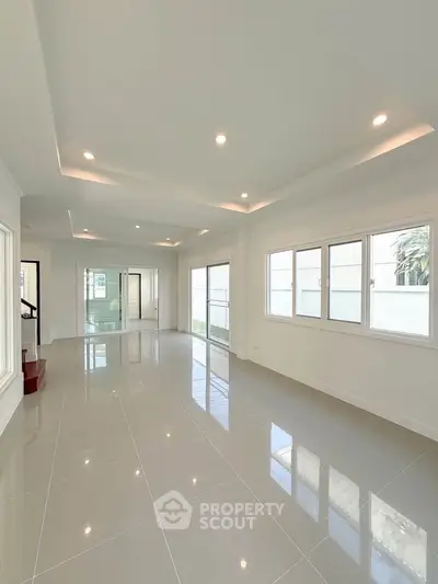 Spacious modern living room with large windows and glossy tiled floors, perfect for natural light and open living.