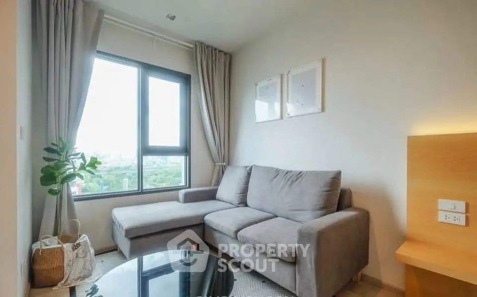 Cozy living room with modern gray sofa and large window offering scenic views.