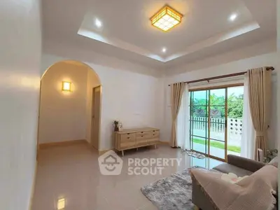 Spacious living room with modern lighting and garden view, perfect for relaxation.
