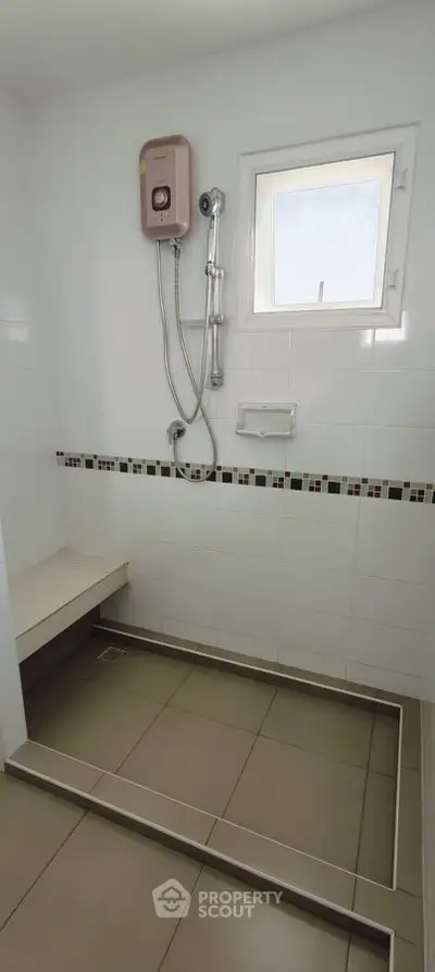 Modern bathroom with shower and window, featuring sleek tile design and built-in bench.