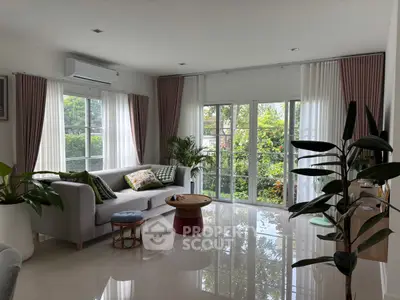 Spacious living room with large windows and garden view, featuring modern furniture and elegant decor.