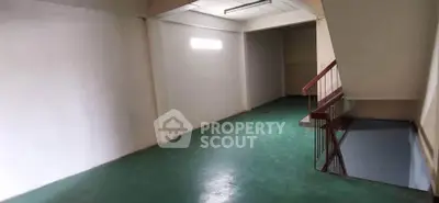 Spacious interior space with green flooring and staircase, ideal for storage or creative use.