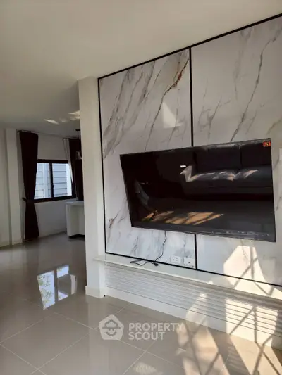 Modern living room with marble accent wall and mounted TV, spacious and bright interior.