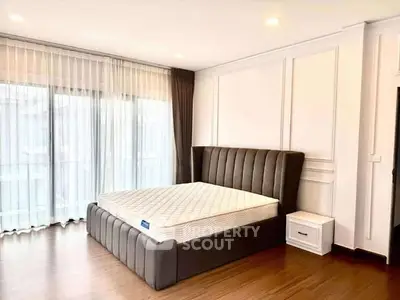 Spacious bedroom with elegant bed and large windows for natural light.