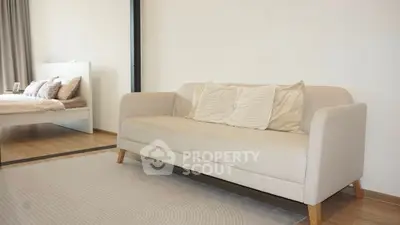 Modern living room with stylish beige sofa and cozy bedroom view