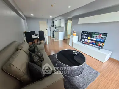Modern living room with open kitchen, stylish decor, and entertainment setup.