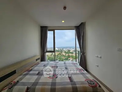 Spacious bedroom with stunning city view and large window, perfect for relaxation and comfort.