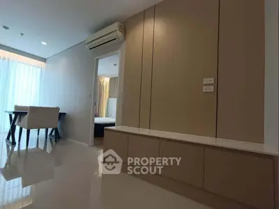 Modern apartment interior with sleek design and natural light, featuring a dining area and bedroom entrance.