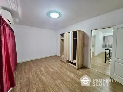 Spacious and well-lit living room with polished wooden flooring, crisp white walls, and modern air conditioning unit, perfect for comfortable urban living.