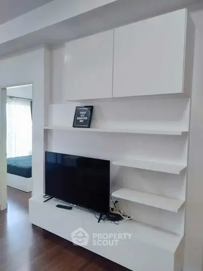 Modern living room with sleek white entertainment unit and flat-screen TV, showcasing minimalist design.