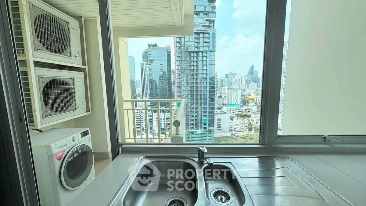Modern kitchen with city view, featuring stainless steel sink and washing machine, perfect for urban living.