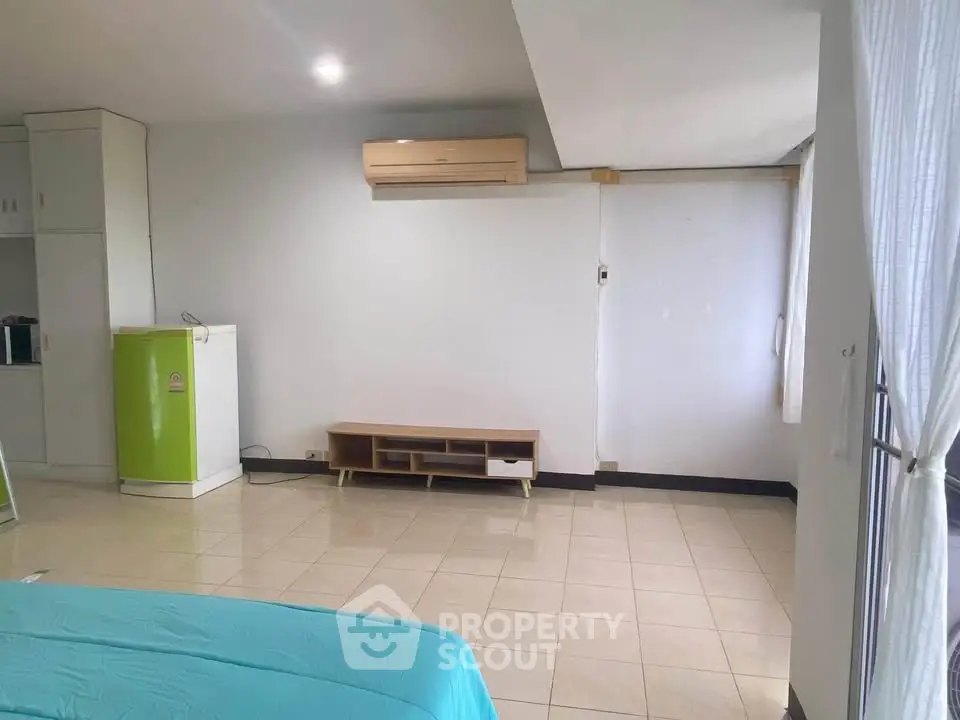 Spacious bedroom with air conditioning and tiled floor, featuring a small kitchenette area.