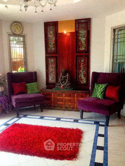 Elegant living room with vibrant decor, featuring purple chairs, red rug, and Asian-inspired art pieces.