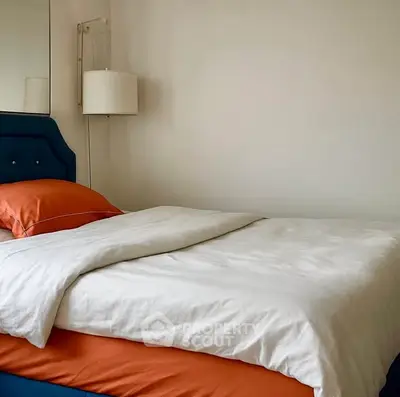 Cozy bedroom with stylish blue headboard and modern lamp, perfect for relaxation.
