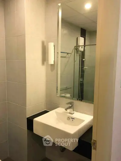 Modern bathroom with sleek sink and large mirror in contemporary apartment.