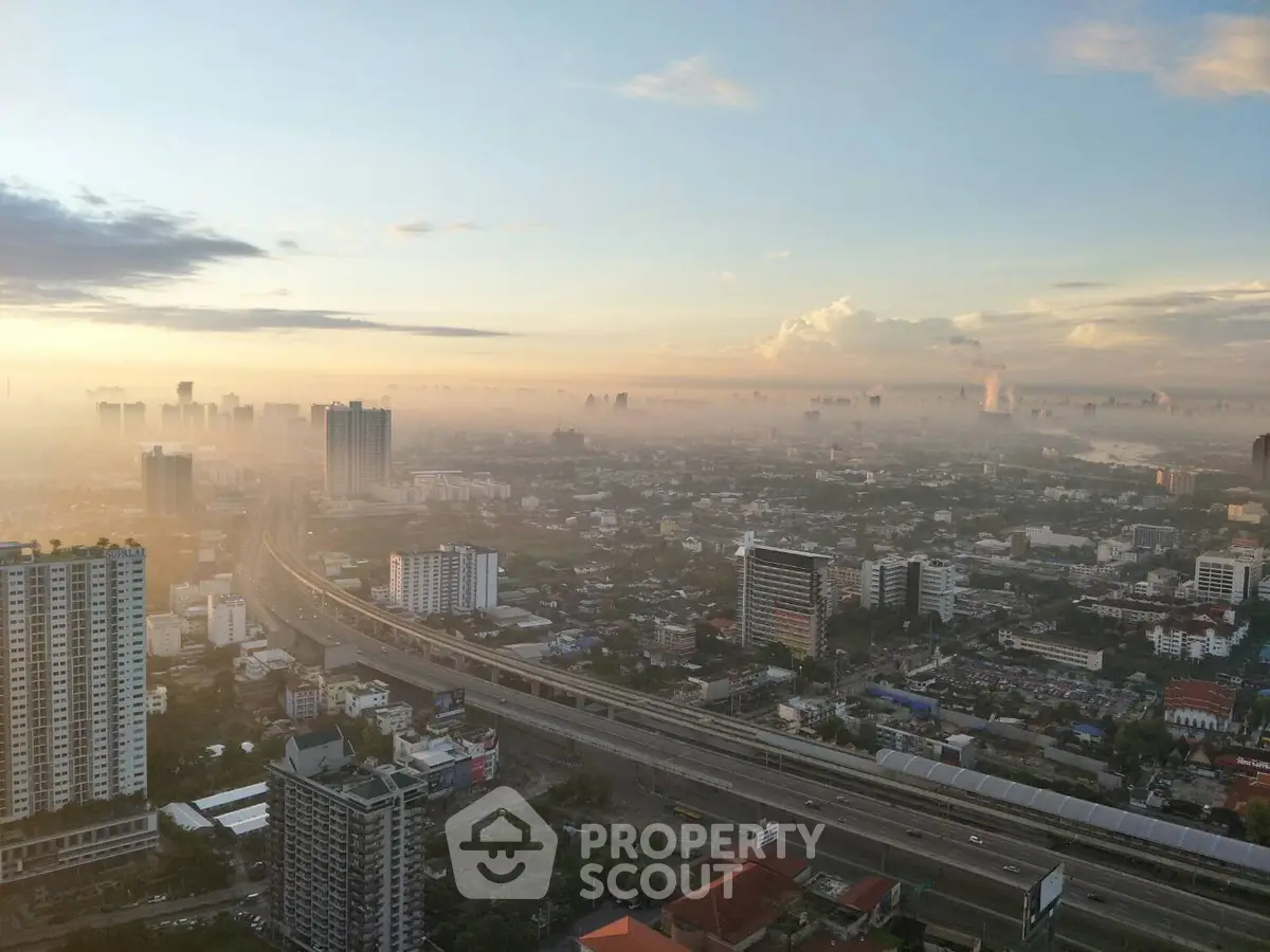 Stunning cityscape view from high-rise building at sunrise, showcasing urban skyline and highway.
