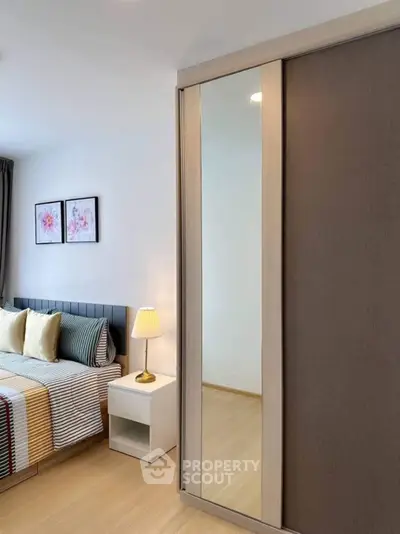 Modern bedroom with stylish decor and mirrored wardrobe in a cozy apartment.