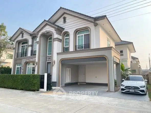 Elegant two-story house with a spacious driveway and luxury car parked, showcasing modern architecture and lush greenery.
