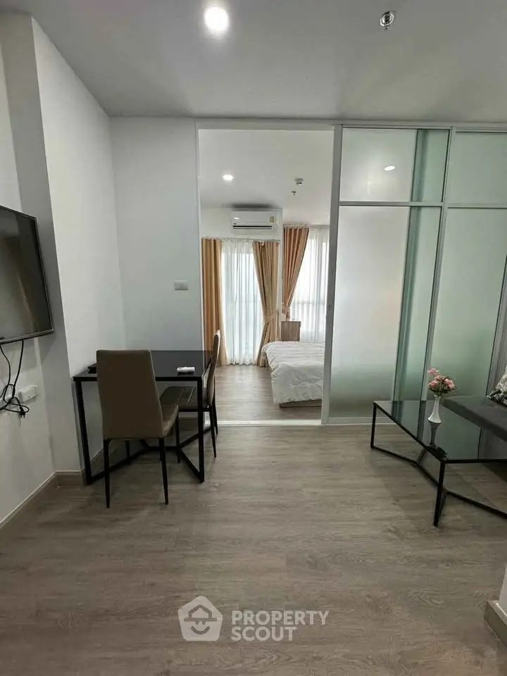 Modern apartment interior with open layout, featuring a cozy living area and stylish bedroom separated by glass doors.