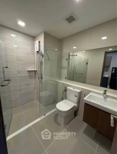 Modern bathroom with glass shower enclosure and sleek fixtures in contemporary apartment.