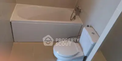 Modern bathroom with sleek bathtub and toilet in minimalist design.