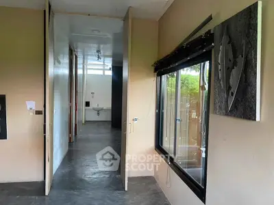 Modern hallway with large windows and contemporary art, leading to a sleek bathroom.